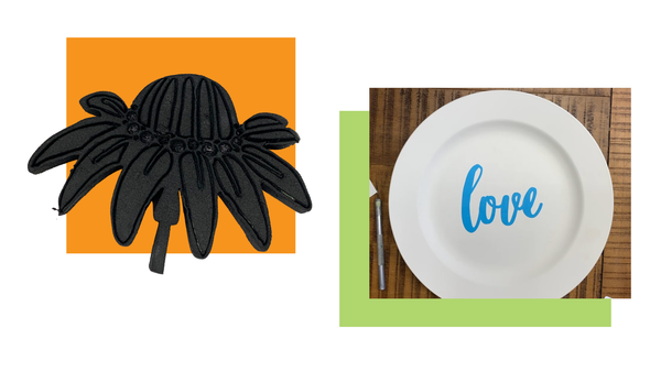 Black flower stamp on an orange square and a white plate with 'love' sticker on a wooden table.